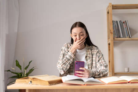 virtual bullying concept, scare teenager, bad news in message from social network, online smartphone user, addiction and cyberbullying, private message to girl at homeの写真素材
