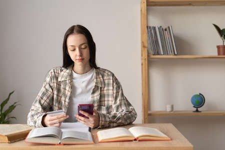 Online shopping concept, girl paying online order with credit card and smartphone, cashless payment system use at home, shopper, ticket bookingの写真素材