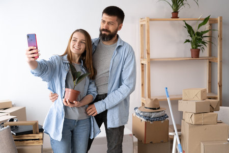New apartments, happy couple taking selfie after moving to new house, family relocation - man and...