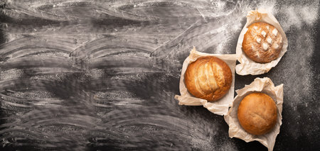 rustic loaves of bread on a black background with flour, homemade fresh pastries, wheat bread...