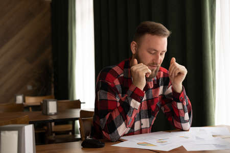 Portrait of frustration businessman learning financial data document at home office. Tired male professional looking papers at workplace. debt notification, bad financial reportの写真素材