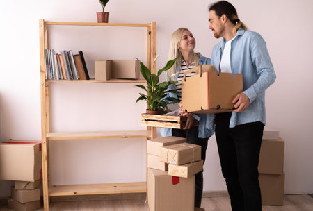 Couple moving into new apartment. Young couple with boxes moving in new flat. Lot of packing cartons...