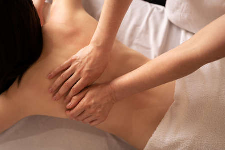 masseur massaging back of young client on massage table, high angle view, wellness treatments at the spaの写真素材