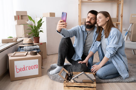 Close up portrait of excited rejoicing joyful attractive carefree lovely cute couple taking picture in new apartment. photo on the smartphone. Photographer partners move houseの写真素材