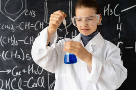 Portret of serious girl in white uniforms conducting chemical experiments in a laboratory. Young scientists. Natural sciences. school education of children.の写真素材