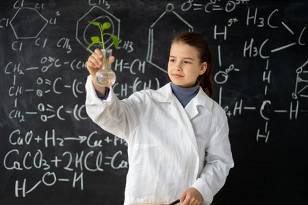 Young student studying small plant in flask in elementary sciences lesson, science laboratory or biotechnology, kids science educationの写真素材