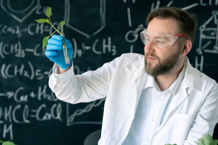 Male microbiologist working in laboratory examining plants in test tube, conducting experiments in laboratory glass, microbiology and genetics conceptの写真素材