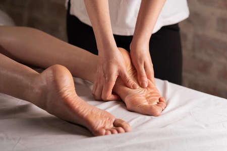 woman foot massage in spa salon, massage therapist massaging feetの写真素材