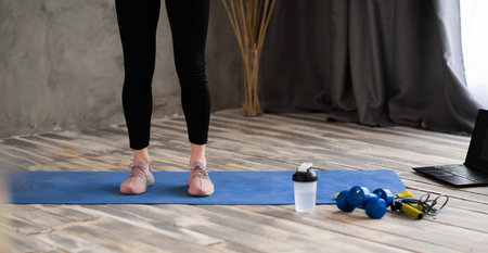Fitness kit at home. Fitness mat, female legs, weights for arms and legs, dumbbells and bottle lie...
