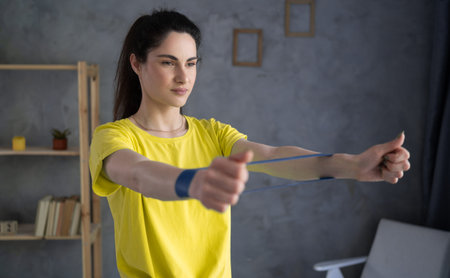 portrait of sporty woman workout with rubber resistance band, performs exercises for the muscles of...