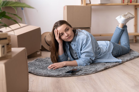 happy smiling caucasian woman with boxes lying on floor at new home and dreaming. people moving new...