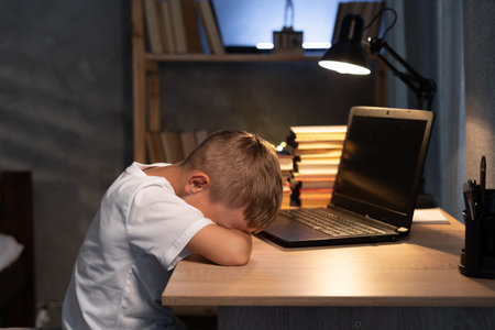 Distance learning online education. Tired caucasian boy studying at home, sleep and lying on laptop...