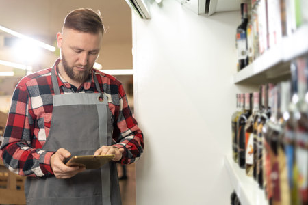 supermarket worker using digital tablet, grocery store employee orders groceries online, innovative technology and workの写真素材