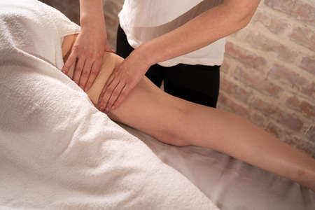 Anti-cellulite massage in the spa salon. The masseur massages thigh and legs. woman massage to reduce cellulite.の写真素材