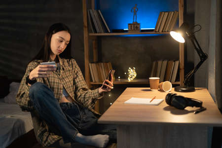 Asian girl holding credit card and using phone at home at night. Online shopping, E-commerce, Internet banking, spending moneyの写真素材