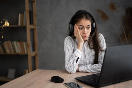 Young hispanic woman watching scary movie, hiding face in fear, online film service, female in panic feels unhappy failureの写真素材