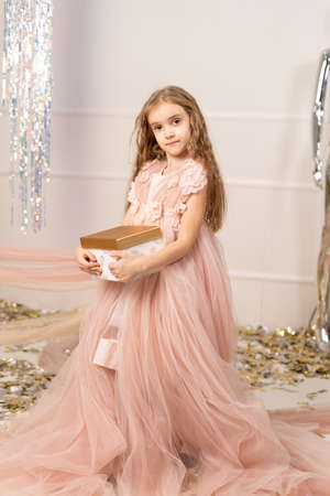 Childrens birthday, little girl with a gift box, decoration with pink, happy children celebrate the holiday, festive pink partyの写真素材