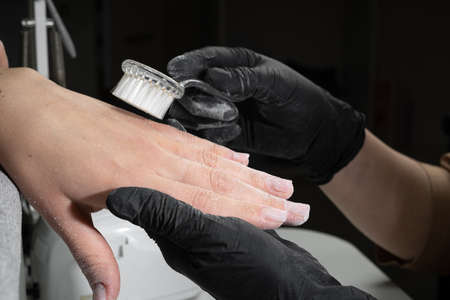 Close-up of manicurist hands is removing dust from nails with a brush to cleaning in manicure salon. Hardware manicure. Care for handの写真素材