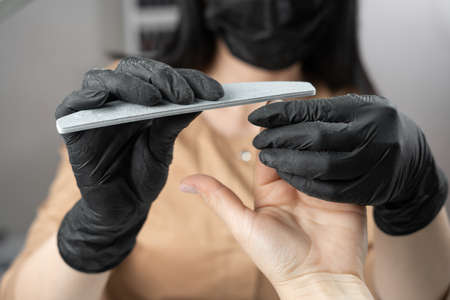 manicurist cut nails with nail file at manicure salon for womanの写真素材