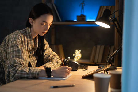 Asian serious girl is studying online via the internet on tablet digital while sitting at home at night. online learning at homeの写真素材
