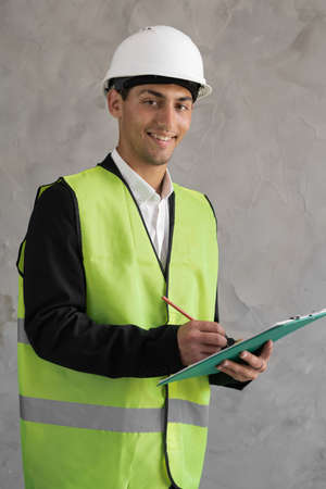 Muslim young engineer taking note on clipboard, portrait of an engineer in a white helmet, male architect writing on clipboardの写真素材