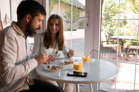 Beautiful couple having breakfast in a stylish cozy cafe, healthy family breakfastの写真素材