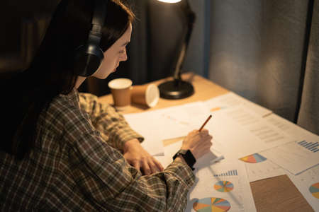 Business consultant working at night on investment issues at home, student analyzing the companys balance sheet report with documents graphics. office, money and taxesの写真素材