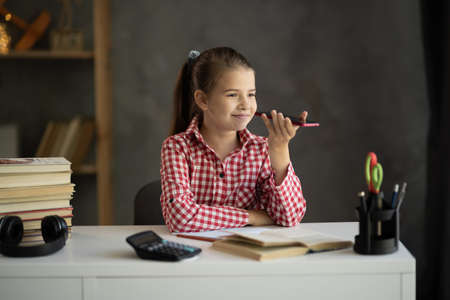 Little girl talking on mobile phone on speaker, recording audio message, using virtual voice assistant for Internet searchの写真素材