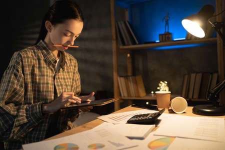 Startup small business entrepreneur Asian girl small business owner using tablet at late evening, work at home at nightの写真素材