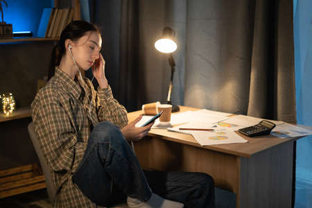 teenager girl listening music while sitting at a deskの写真素材