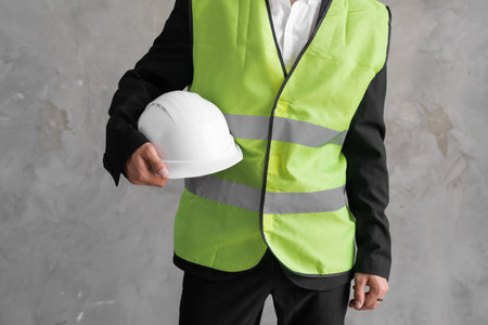 Close-up workwear and helmet in engineer or constructor hand as safety uniform with copy space on grey backgroundの写真素材