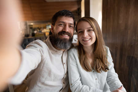 Smiling beautiful woman and her handsome boyfriend. Couple at their date in restaurant. cheerful family. They taking Pov selfie at cafeの写真素材