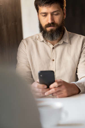 Portrait of man using smartphone in cafe, business freelanceの写真素材