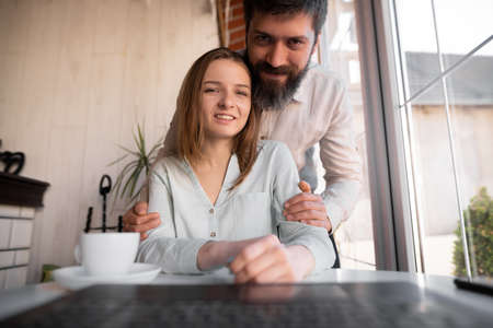 Happy young european couple resting at living room, waving hand hello using webcam laptop, greeting friends at online video call distant meeting, app screenの写真素材