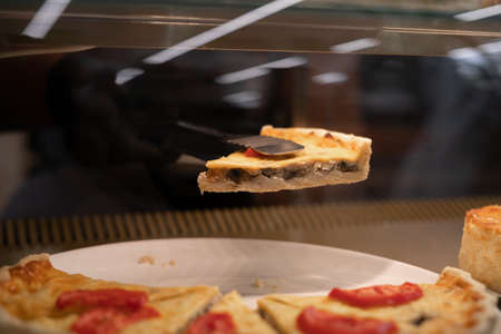 meat pie on showcase display in cafe, bakers hand takes savory pastries from refrigerator, close-up view, cafe businessの写真素材