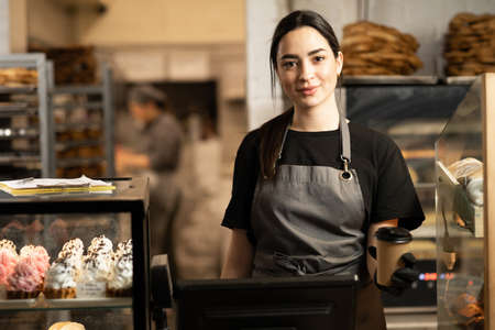 woman business owner with bakery shop background near showcases with pastriesの写真素材