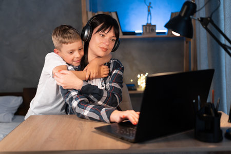 Working at home with kids. Young focused woman mother using laptop and thinking about work task...