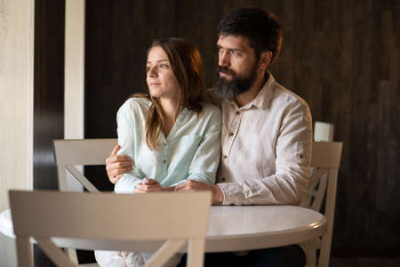 Handsome man and woman are sitting in a cafe by the window, romantic date indoor coffee shop, dreaming couple husband and wife by windowの写真素材