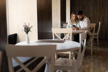 Couple in cafe using mobile phone online shopping, internet browsing in restaurant, man and woman on date with smartphoneの写真素材