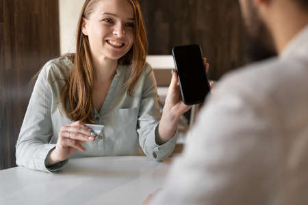cell phone blank screen mockup.Happy woman hand holding texting using mobile on desk at cafe and man near. background empty space for advertise.people contact marketing businessの写真素材
