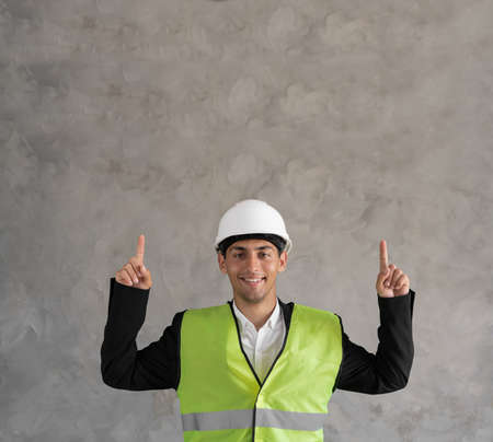 Young muslim architect man wearing builder safety helmet over isolated background pointing fingers up. Exited and happy.の写真素材