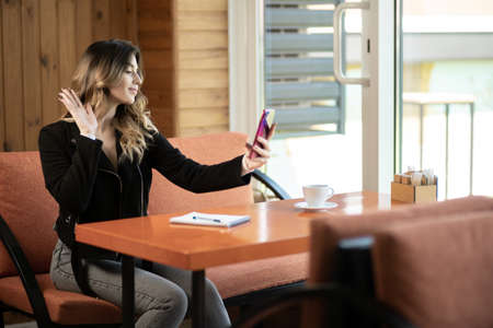 young beauty girl make selfie for smartphone sitting at cafe, indoors portrait, fashion model, pretty girl, make upの写真素材