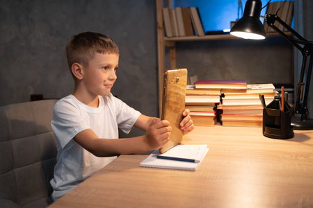 student boy with digital tablet computer learning online at home at night. children, education and technologyの写真素材