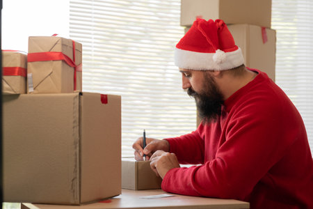 Confident young businessman Santa Claus working in online store for business. Small business owner at his desk. online shop christmas sale. SME and dropshippingの写真素材