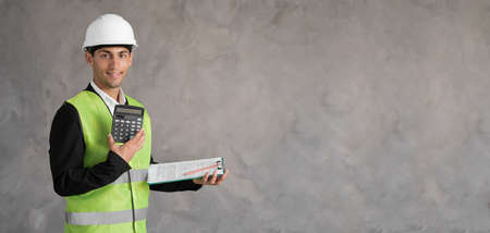 architect working on blueprint. Muslim engineer wearning in helmet on workplace with calculator and blueprints. Builder isolated on grey background. Engineer conceptの写真素材