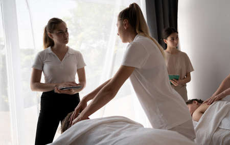 Teacher helping student training to become masseuse, women doing back massage to patientの写真素材