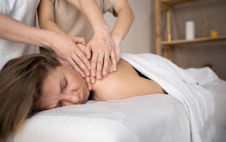 Woman having four hands massage, female hands massaging girls shoulders, relaxing massage training, masseur work conceptの写真素材