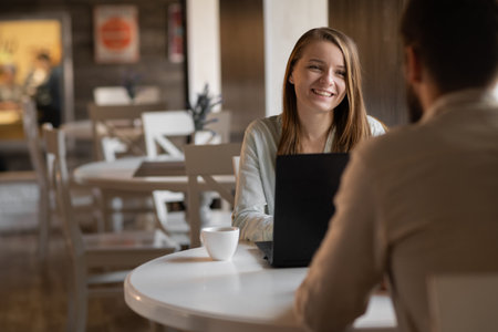 Young couple working on laptop in cafe. Handsome young man and attractive woman are spending time together. Coworking and freelanceの写真素材