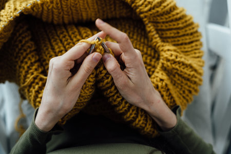 Close-up of female hands knitting wool sweater. Woman knits from thick yarn. Handmade clothes. The girl goes in for her hobbies. Knitting concept.の写真素材