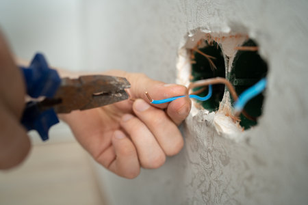 man works with electrical wires using tools, fixing socket at home, male household work with electricity, pliers and wire cutters in mans hands, electrician with wireの写真素材
